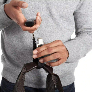 Person attaching a digital scale for luggage to a travel bag handle before weighing luggage.