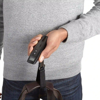 Close-up of a digital scale for luggage lifting a travel bag for accurate weight measurement.
